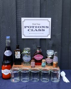 bottles and glasses are lined up on a table with a sign in the background that says first year potions class