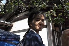 a young woman standing under a tree next to a building