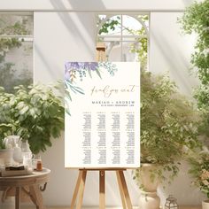 an easel with a wedding seating chart on it in front of potted plants