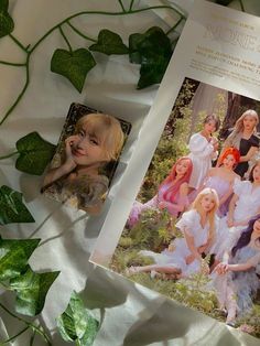 an open magazine with photos of women in white dresses and green leaves on the table