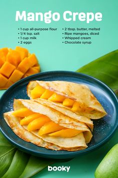 mango crepe on a blue plate next to sliced mangos and green leaves