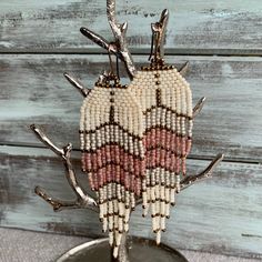 a beaded heart hanging from a tree branch on top of a wooden table next to a wall