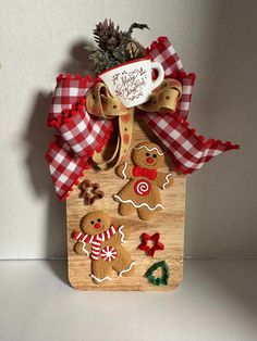 a wooden board with gingerbreads and cookies on it, tied to a red checkered ribbon