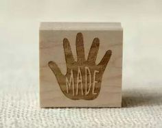 a wooden stamp with the word made written on it, and a hand drawn in brown ink