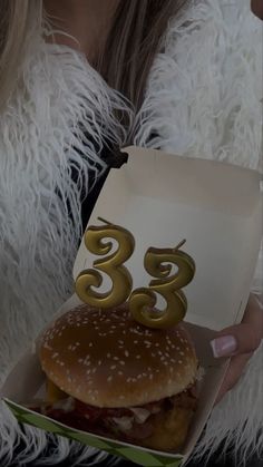 a woman is holding a hamburger with the number three on it