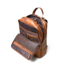 Crafted from buffalo top grain leather, this backpack is a perfect blend of fashion and functionality. Handcrafted with smooth finishing using premium top-grain leather, it's an ideal companion for trekking or any adventure. This Transit backpack doubles as a laptop bag for office or college, featuring two large central compartments with multiple pockets for organized storage. The canvas lining inside and at the back adds a rugged touch. With a strong durable handle and shoulder straps, it ensur Business Backpack With Waxed Finish, Leather Backpack For Business Trips With Luggage Sleeve, Leather Backpack With Luggage Sleeve For Business Trips, Leather Backpack For Business Trips, Rugged Laptop Bag For Travel, Brown Leather Backpack For Business Trips, Organized Storage, Buffalo Leather, Top Grain Leather