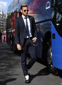 a man in a suit and tie standing next to a blue double - decker bus