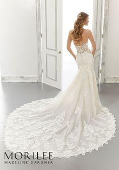 a woman in a wedding dress is looking at her reflection in the mirror while she stands near an open door