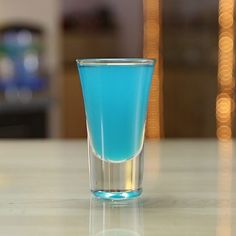 a shot glass filled with blue liquid on a table