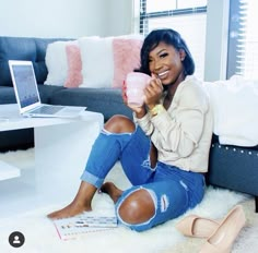 a woman sitting on the floor holding a cup