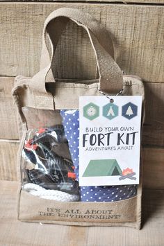 a bag with some items in it on top of a wooden table next to a sign that says build your own fort kit