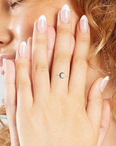 a woman holding her hand up to her face with the moon tattoo on it's ring