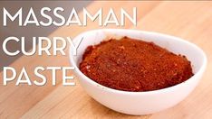 a white bowl filled with curry paste sitting on top of a wooden table next to the words massaman curry paste