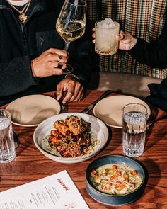 two people sitting at a table with food and drinks