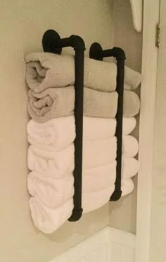 towels are hanging on the wall in a bathroom with two black towel racks and one white towel rack