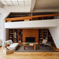 a living room filled with furniture next to a tall white book shelf on top of a hard wood floor