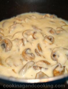 mushrooms cooking in a skillet on top of the stove with white sauce over them