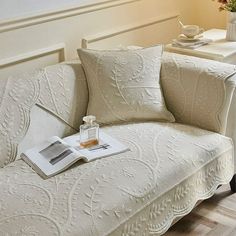 a white couch sitting in a living room next to a table with a vase on it