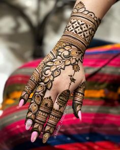 a woman's hand with henna tattoos on her arm and hands, all decorated in