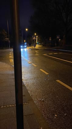 an empty street at night with the lights turned on and no one is in it