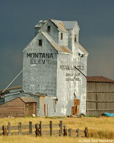 an old grain silo sits in the middle of a field with other farm buildings