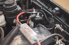 the engine compartment of an old car with its hood up and wires attached to it