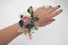 a woman's hand with flowers and leaves on it, holding onto her wrist