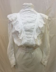 "1890s, 36\" bust, white cotton batiste lace edge blouse ( waist) .  The blouse has pin tucked pleated front, high collar and ruffled yoke.  Sleeves are full mutton chopped with elaborate lace inserts and lace cuffs.  Unfinished bottom meant to be tucked into skirt.  Blouse is fastened in back  with 14 hand crochet buttons.  Hook and eye at top of collar  in back.   Measurements: bust 36\" Waist 26\" Shoulder to shoulder  15\" Shoulder to hem  19\" Sleeves 19\" long Arm holes 7\" Width at bottom Historical Victorian Dress With Ruffles, White Fitted Victorian Blouse, Fitted White Victorian Blouse, Fitted Ruffles Blouse For Gatherings, Fitted Ruffled Blouse For Gatherings, Fitted Ruffle Blouse For Gatherings, Classic Fitted White Victorian Dress, Classic White Victorian Dress With Ruffles, White Fitted Classic Victorian Dress