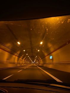 a car driving through a tunnel with lights on at the end is seen from inside