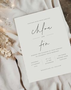 the wedding stationery is laid out on top of white linens with lights in the background