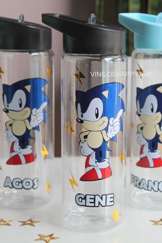 three glass cups with cartoon characters on them sitting on a table next to each other