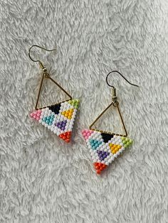 a pair of earrings with multicolored beads hanging from them on a white surface