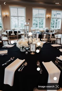 a black table with white flowers and silverware on it is set up for a formal function