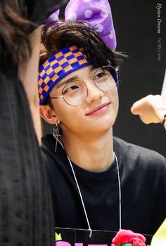 a boy with glasses and a purple bow on his head is looking at another person