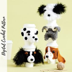 three knitted dogs sitting next to each other in front of a coffee cup and yarn ball