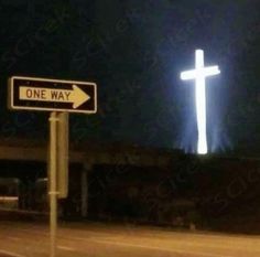 a one way street sign in front of a cross