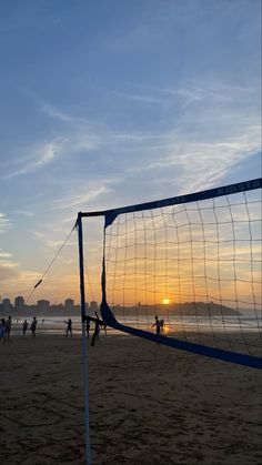 people playing volleyball on the beach at sunset