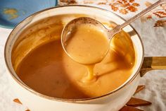 a spoon is being used to dip sauce in a pot on a tablecloth with other items