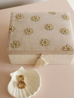 a white box sitting on top of a table next to a seashell and ring