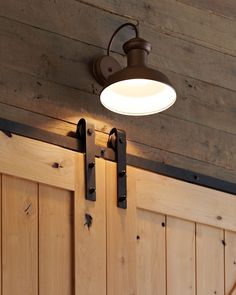 a light that is on the side of a wooden wall next to some wood doors