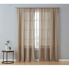 a living room with a window and curtains on the windowsill, next to a small table