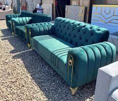 a green couch sitting on top of a gravel covered ground next to other furniture and chairs