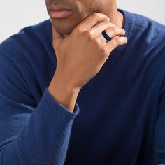 a man in a blue sweater is holding his hand on his chin