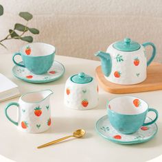 a tea set on a table next to a potted plant