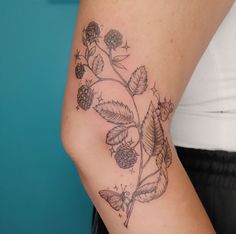 a woman's arm with flowers and leaves tattooed on the left side of her body