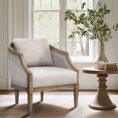 a chair and table in front of a window with a potted plant next to it