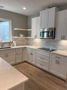 a kitchen with white cabinets and wood floors