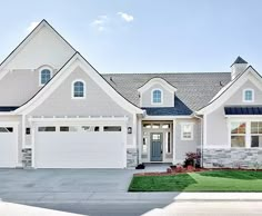 a large white house with two garages on the front and one car door open