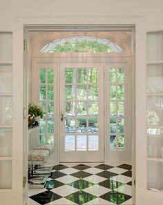 an entry way with black and white checkered flooring, glass doors and windows