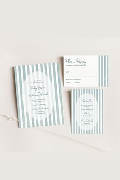 the blue and white striped wedding stationery is laid out on top of each other